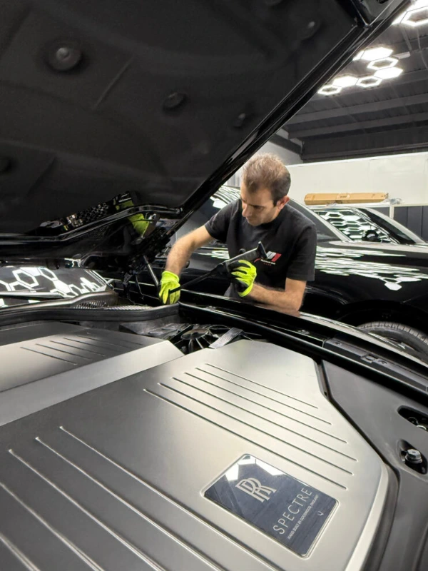 Technician inspecting an engine bay at Platinum One Auto
