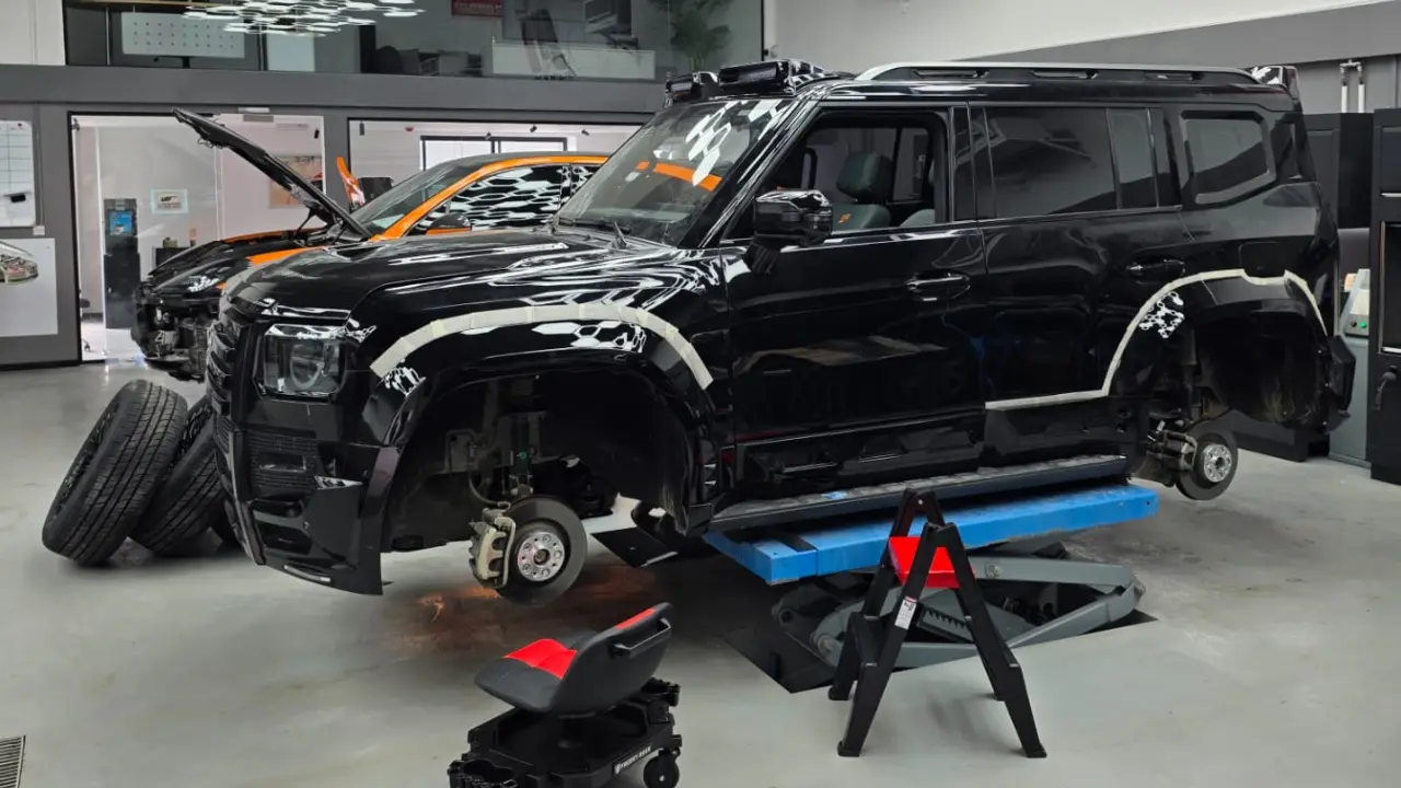 Jetour T2 on a lift with wheels removed during modification and wrap preparation at Platinum One Auto in Dubai