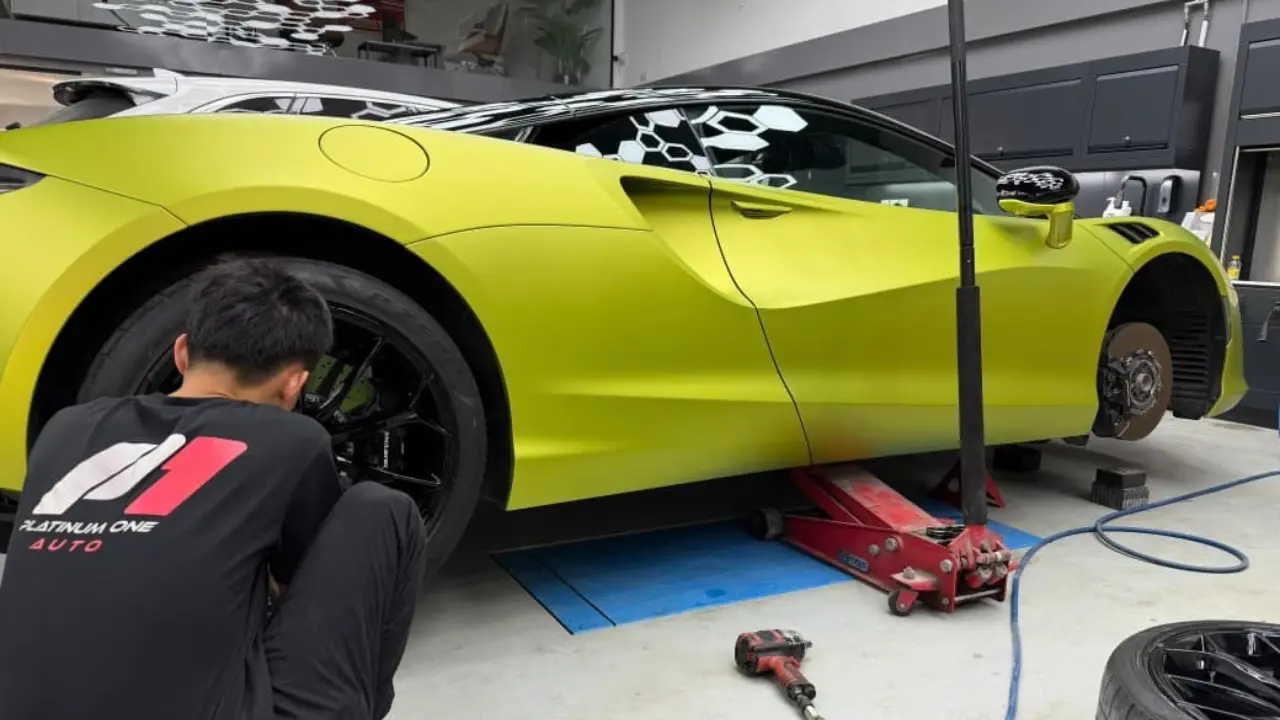 Technician servicing the wheels and brakes of a satin yellow McLaren Artura at Platinum One Auto in Dubai