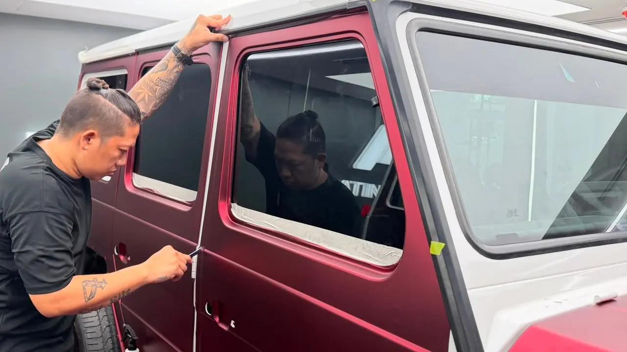 Technician applying satin red film to a Mercedes G-Wagon at Platinum One Auto's workshop in Dubai