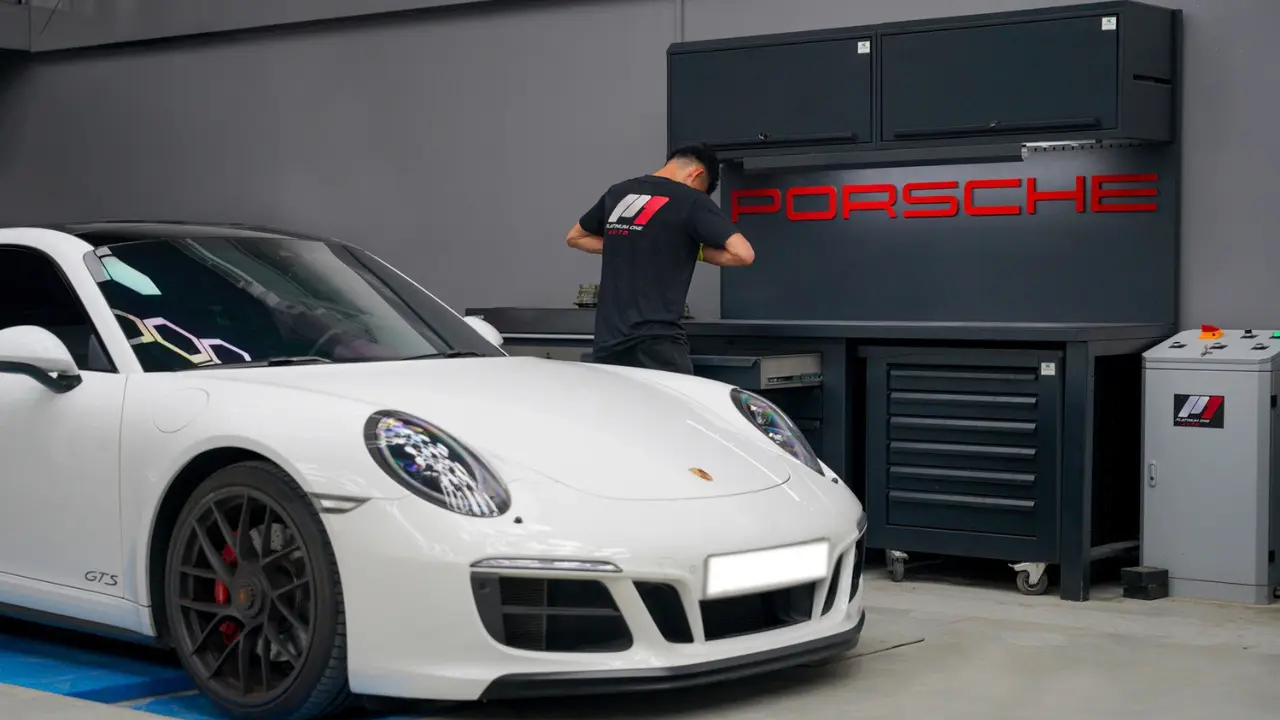 White Porsche 911 GTS in the Porsche service bay at Platinum One Auto's supercar workshop in Dubai