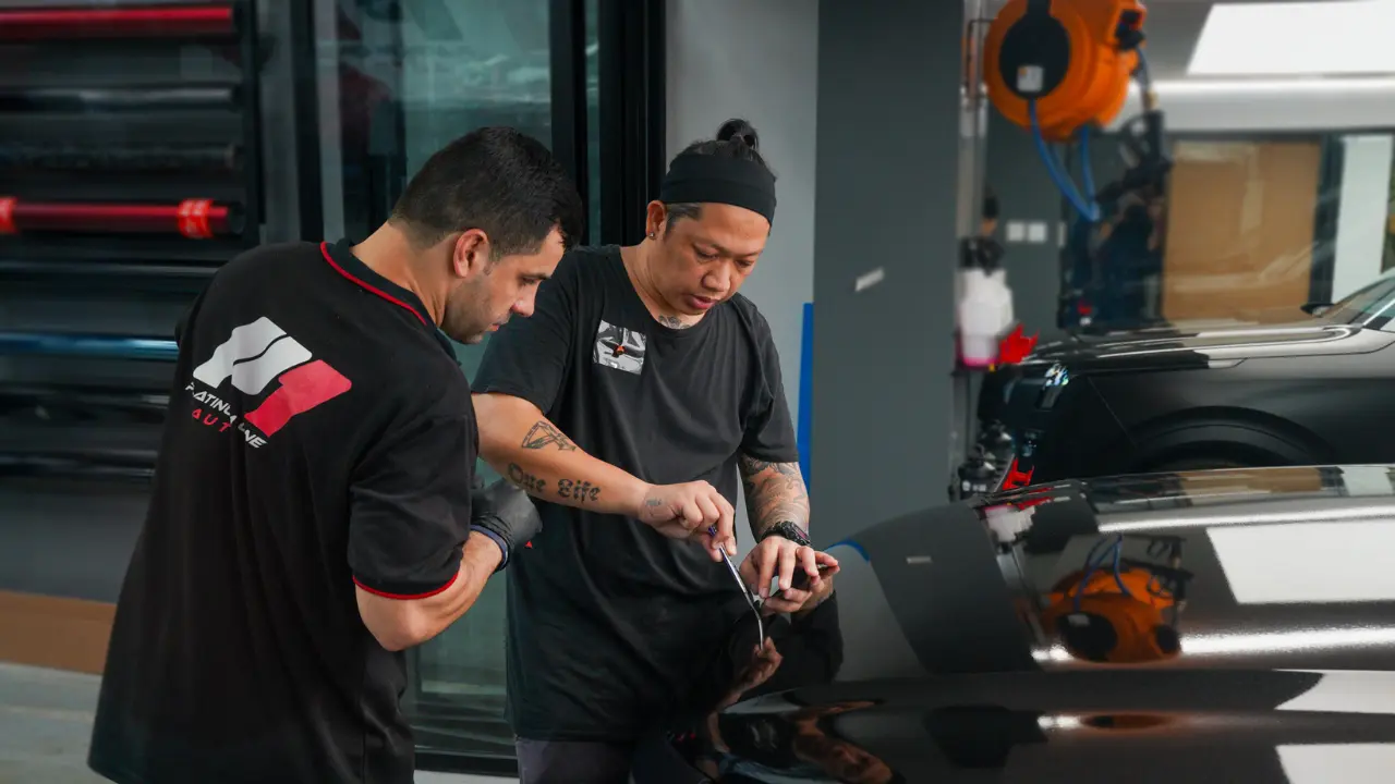 Platinum One Auto technicians trimming film during a PPF installation at the Dubai workshop