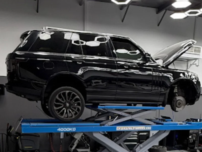 black Range Rover on a hydraulic lift in a repair shop